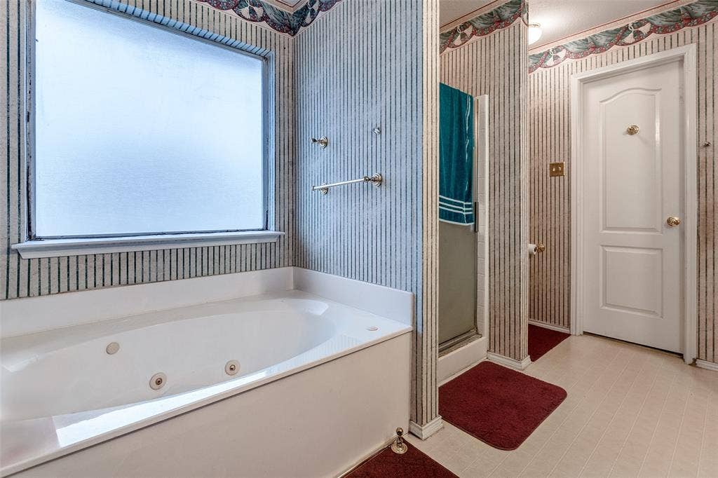 Bathroom with a stall shower, wallpapered walls, and a tub with jets