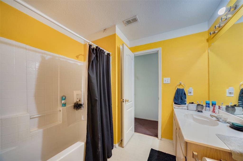 Full bath featuring vanity, shower / tub combo with curtain, and a textured ceiling