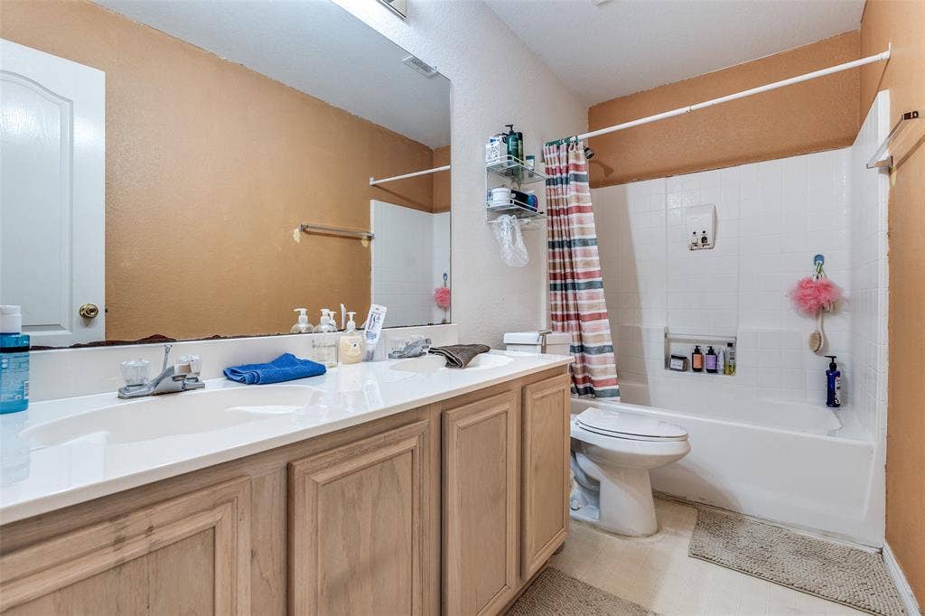 Full bathroom featuring double vanity and shower / bath combination with curtain