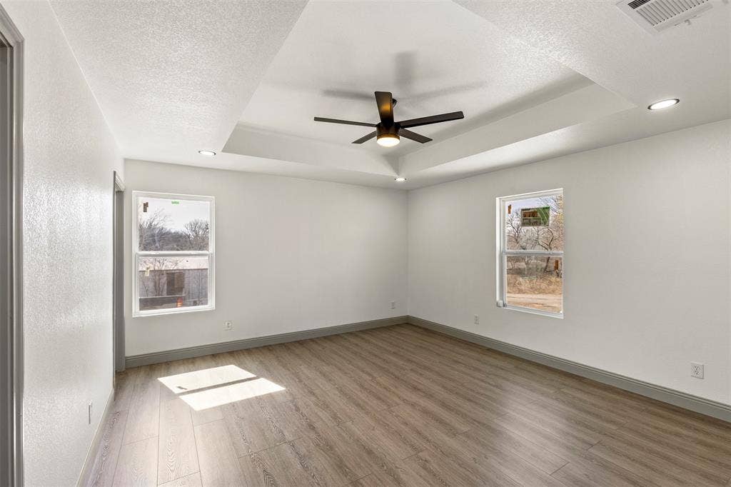 5619 Lake Granbury Trail, Granbury, TX 76048 Empty room with a ceiling fan, light wood finished floors, a textured ceiling, recessed lighting, and a raised ceiling