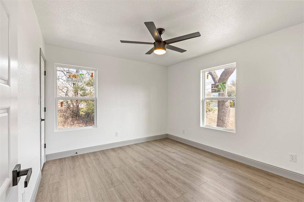 5619 Lake Granbury Trail, Granbury, TX 76048 Unfurnished room with light wood finished floors, a ceiling fan, plenty of natural light, and a textured ceiling