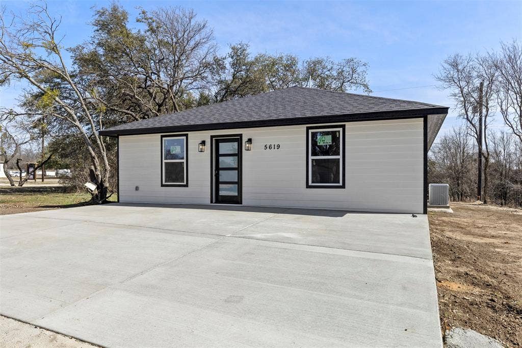 5619 Lake Granbury Trail, Granbury, TX 76048 Single-story residence featuring white horizontal siding, a dark roof, and a prominent concrete driveway