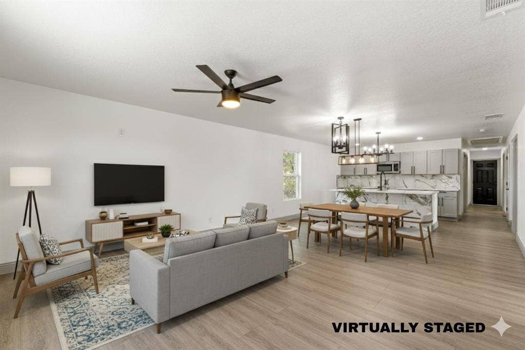 5619 Lake Granbury Trail, Granbury, TX 76048 Living area featuring light wood-style flooring, a chandelier, and a ceiling fan