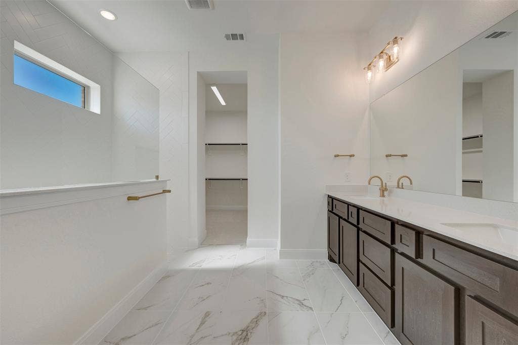 Bathroom featuring a dual vanity with dark wood cabinetry, white countertops, and gold-toned fixtures