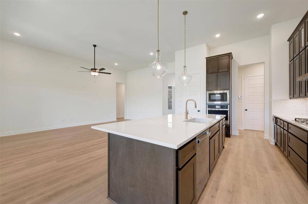 Kitchen island featuring a white countertop, undermount sink, and stainless steel dishwasher
