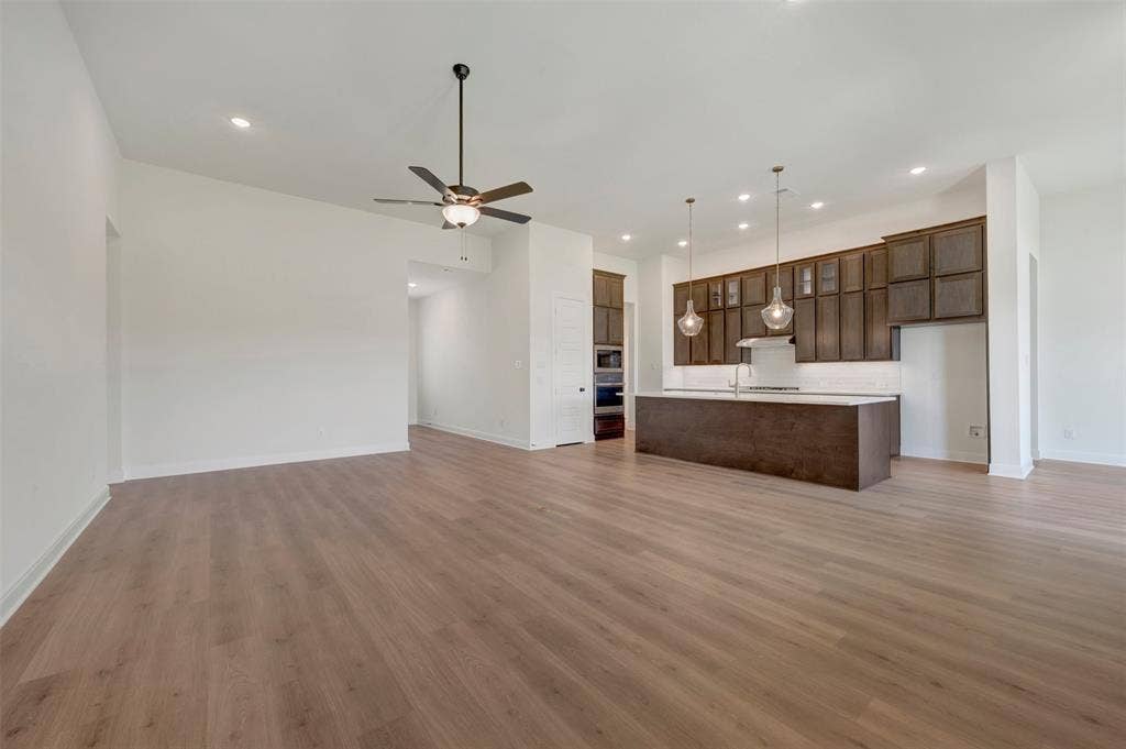 Expansive living space featuring wood-finish flooring, recessed lighting, and a ceiling fan