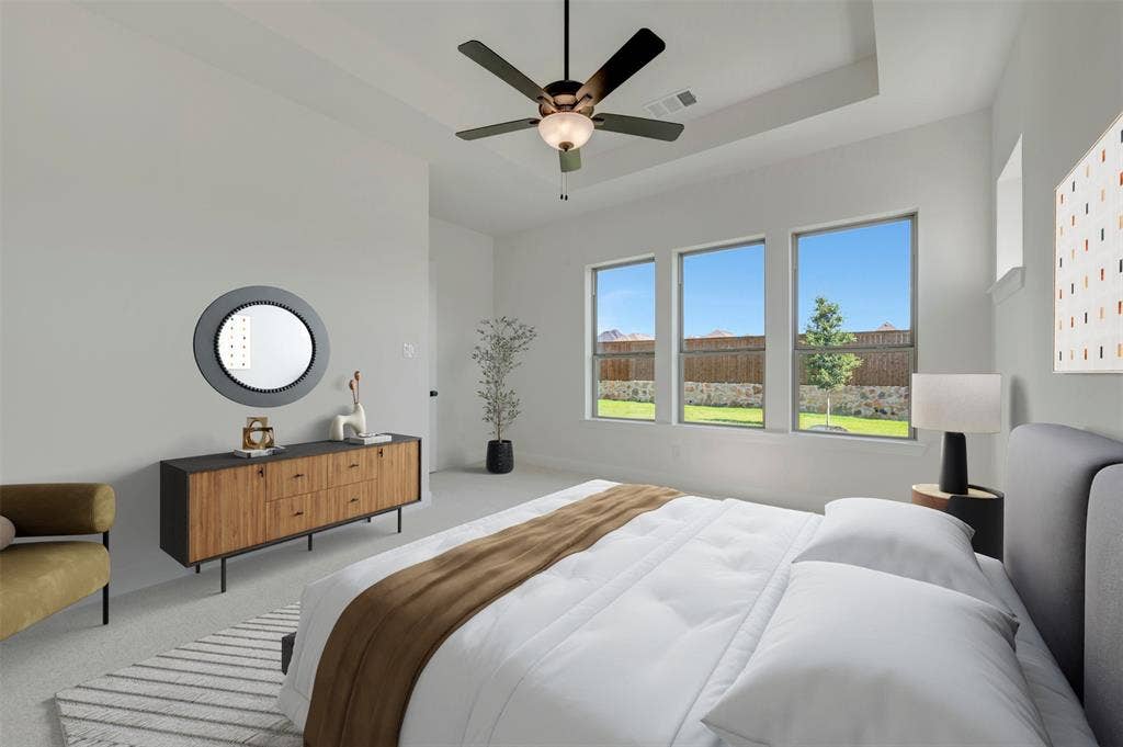 Spacious interior featuring a tray ceiling, ceiling fan with integrated lighting, and three large windows