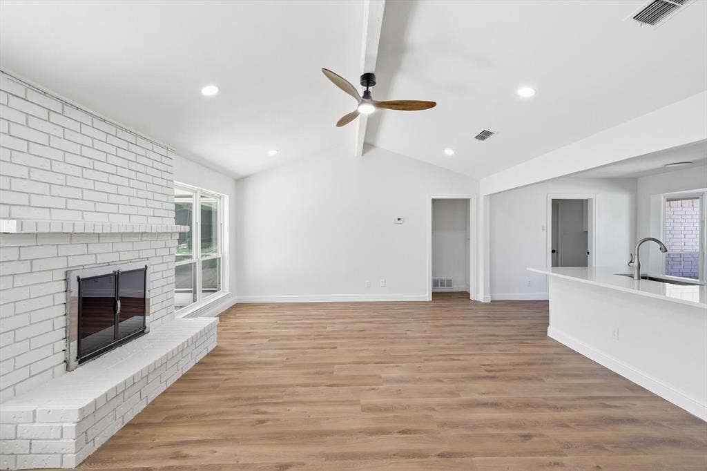 2211 Sierra Drive, Grapevine, TX 76051 Unfurnished living room featuring light wood-style flooring, beamed ceiling, a ceiling fan, a fireplace, and recessed lighting