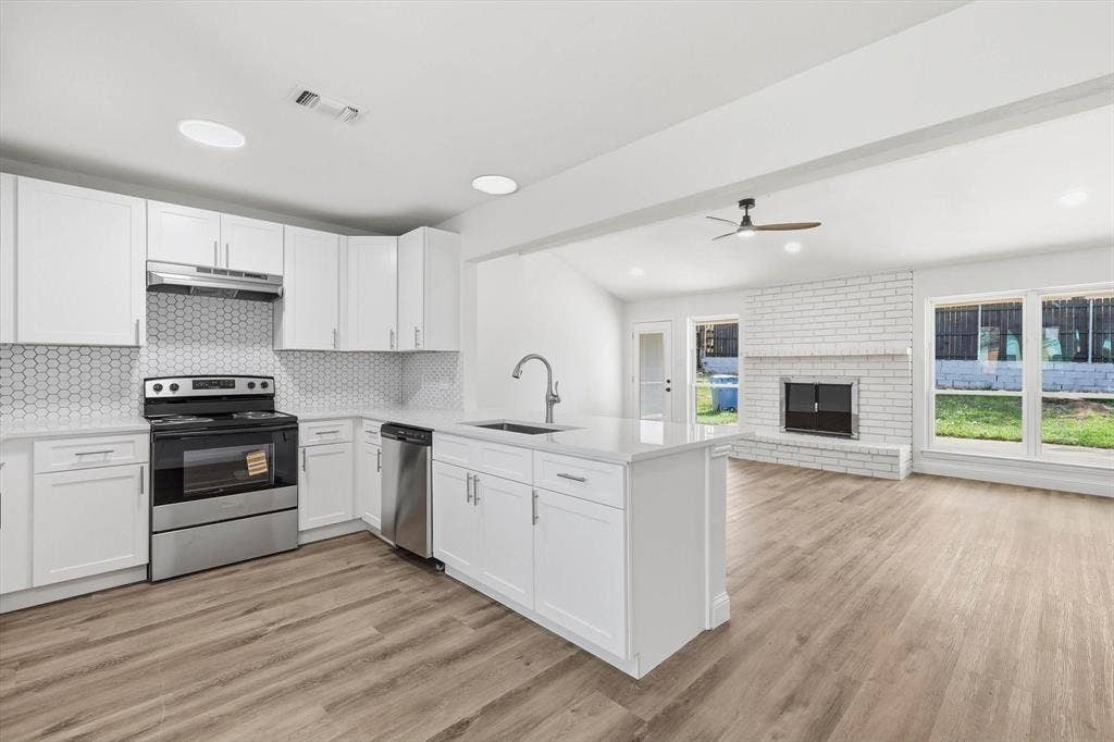 2211 Sierra Drive, Grapevine, TX 76051 Kitchen featuring stainless steel appliances, a fireplace, open floor plan, white cabinets, and recessed lighting