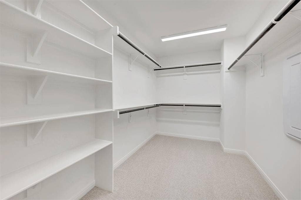 4721 Vizsla Lane, McKinney, TX 75071 Walk-in closet featuring built-in shelving, multiple hanging rods, light-colored carpeting, and recessed lighting