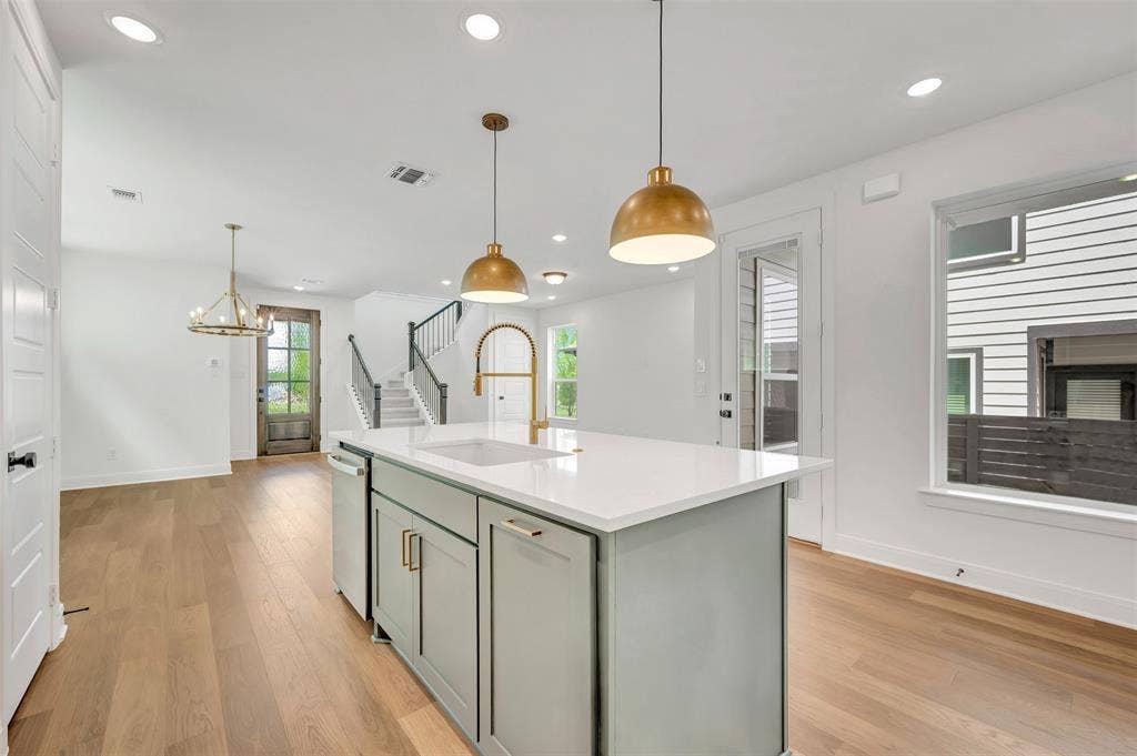 4721 Vizsla Lane, McKinney, TX 75071 Kitchen island with a light grey cabinet finish, white countertop, and gold-toned pendant lighting