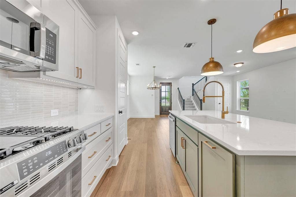 4721 Vizsla Lane, McKinney, TX 75071 Contemporary kitchen featuring a white subway tile backsplash, stainless steel gas range, and white cabinetry with gold-tone hardware