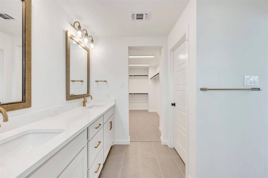 4721 Vizsla Lane, McKinney, TX 75071 Dual vanity with integrated sinks, white cabinetry, brass hardware, and rectangular mirrors with brass-finish frames