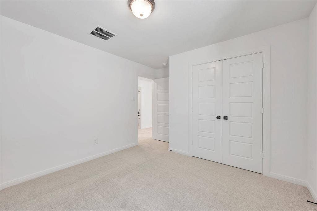 4721 Vizsla Lane, McKinney, TX 75071 Carpeted room featuring white walls, a flush-mount ceiling light fixture, and a pair of paneled bifold closet doors with dark hardware