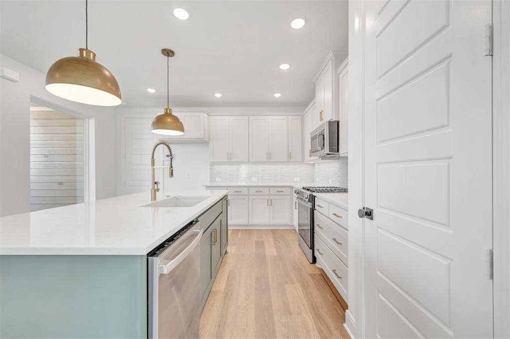 4721 Vizsla Lane, McKinney, TX 75071 Kitchen featuring a large island with a built-in sink and dishwasher, light-toned wood-finish flooring, recessed lighting, and a subway tile backsplash