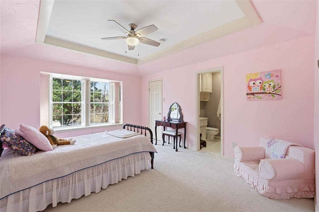 Carpeted bedroom with a tray ceiling, a ceiling fan, and ensuite bath