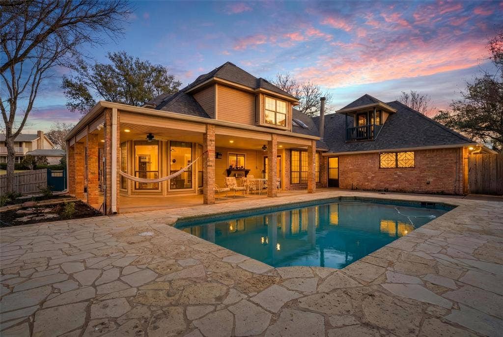 Back of house at dusk featuring a patio and brick siding