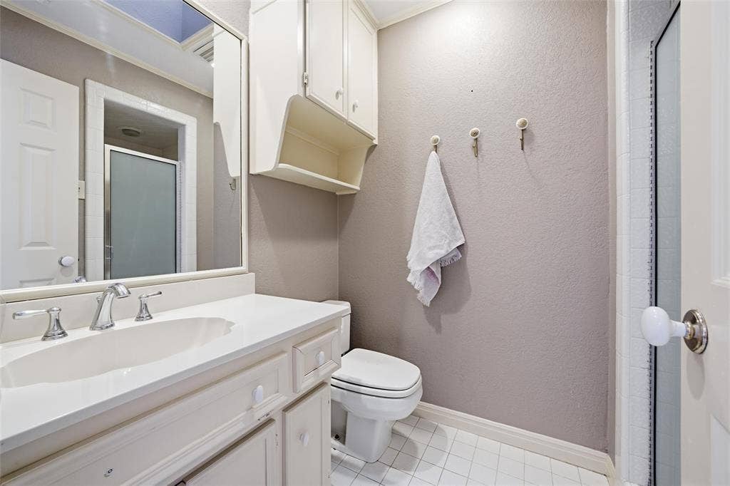 Bathroom with a stall shower, vanity, light tile patterned floors, and a textured wall