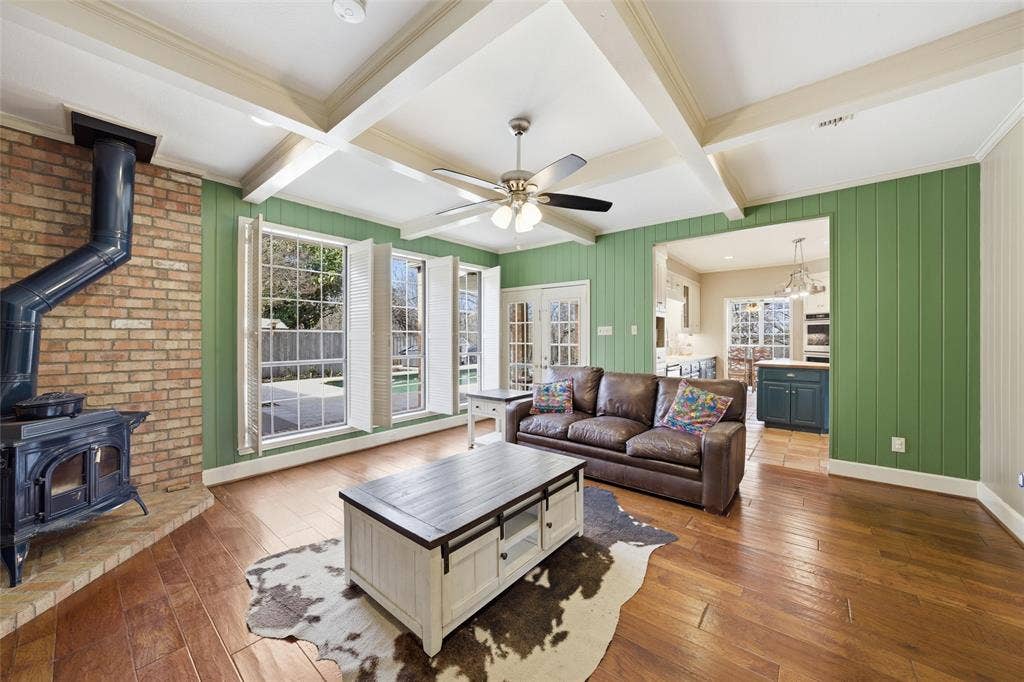 Living area featuring a wood stove, coffered ceiling, light wood finished floors, and ceiling fan