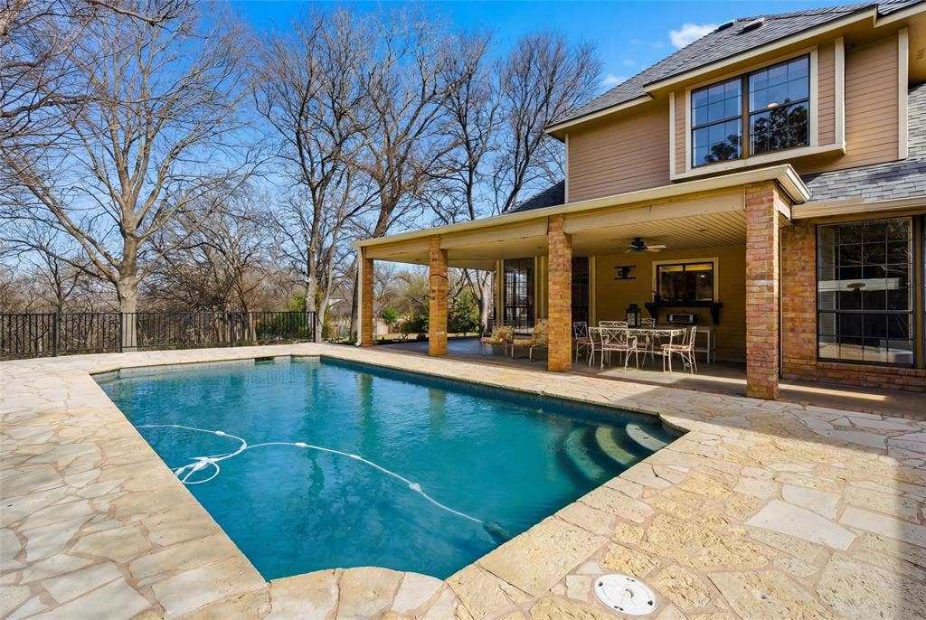 View of pool featuring patio surround, outdoor dining area, and a fenced backyard