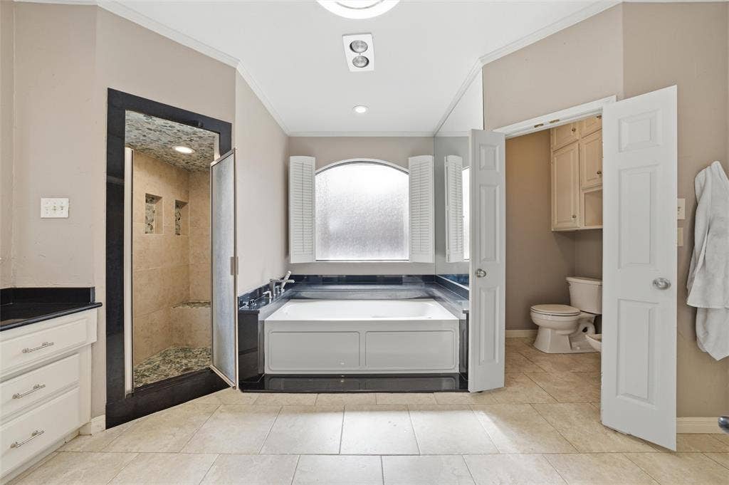 Full bath with crown molding, a stall shower, a bath, light tile patterned floors, and vanity