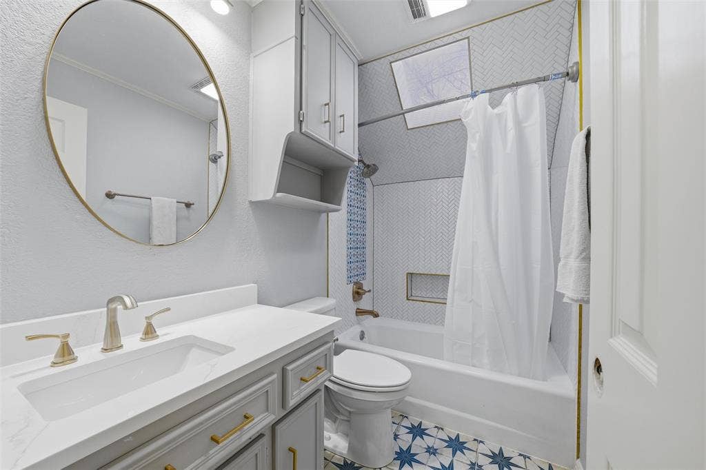 Bathroom with vanity, crown molding, shower / bath combo, and a textured wall