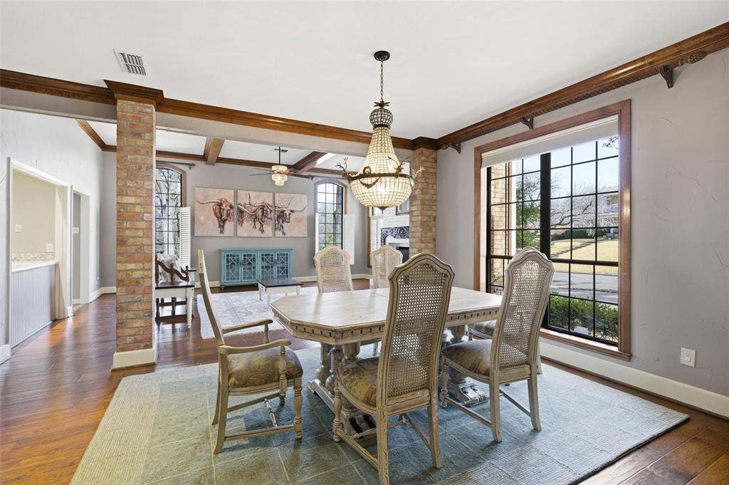 Dining room with dark wood finished floors, beam ceiling, a chandelier, ceiling fan, and ornamental molding