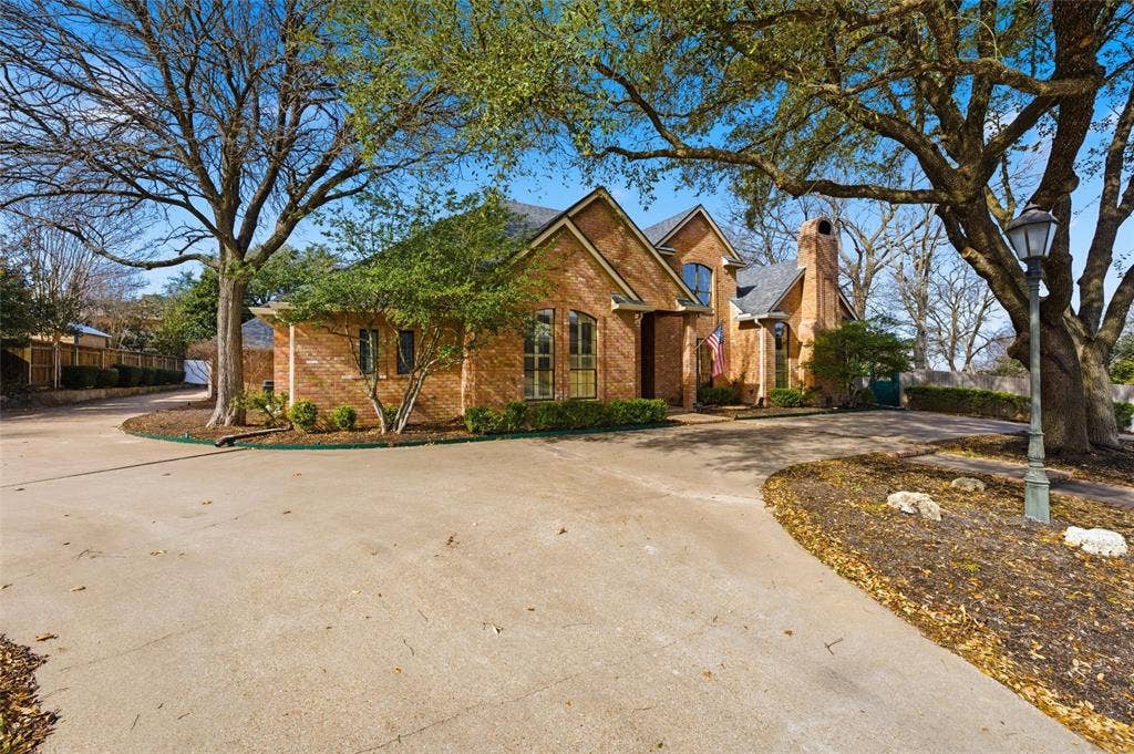 Traditional home with driveway, brick siding, and a chimney