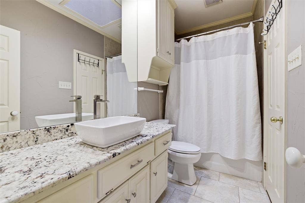 Full bathroom with ornamental molding, vanity, shower / bath combination with curtain, and light tile patterned flooring