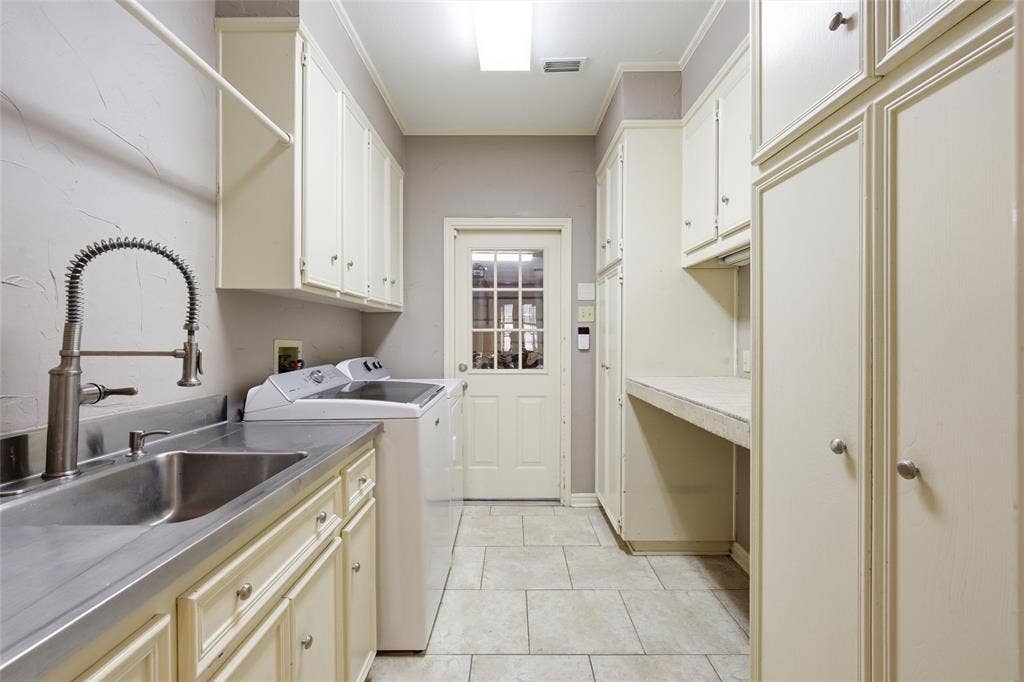Laundry room with crown molding, independent washer and dryer, light tile patterned flooring, and cabinet space