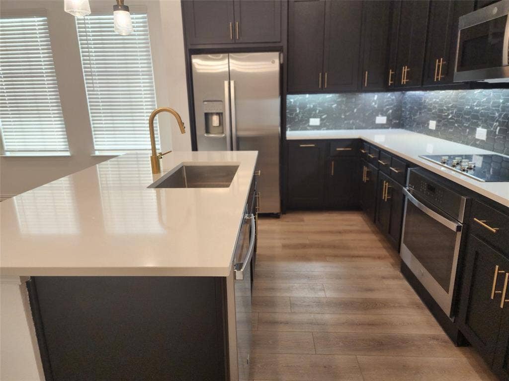 627 Redwood Way, Mansfield, TX 76063 Kitchen featuring stainless steel appliances, an island with sink, backsplash, light wood-type flooring, and hanging light fixtures