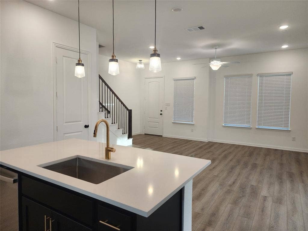 627 Redwood Way, Mansfield, TX 76063 Kitchen featuring dark cabinetry, open floor plan, an island with sink, light wood-type flooring, and pendant lighting