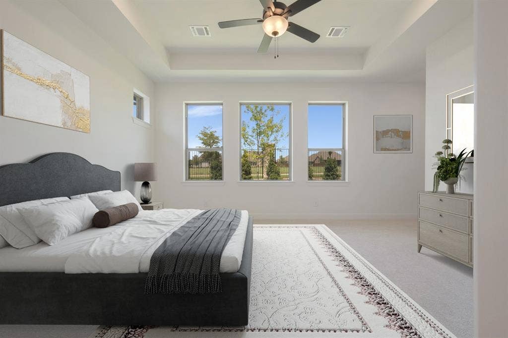 3283 Jersey Drive, Midlothian, TX 76065 Spacious bedroom featuring a tray ceiling, three large windows, a ceiling fan, and light-toned carpet flooring