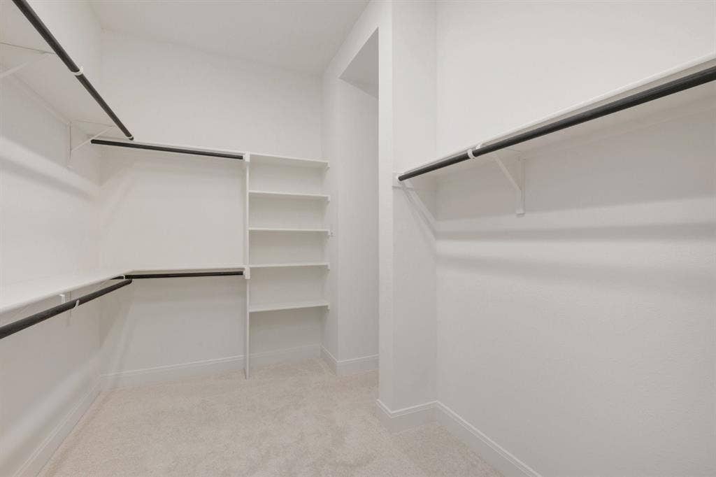 3283 Jersey Drive, Midlothian, TX 76065 Walk-in closet featuring built-in shelving, multiple hanging rods, and light-toned carpeting