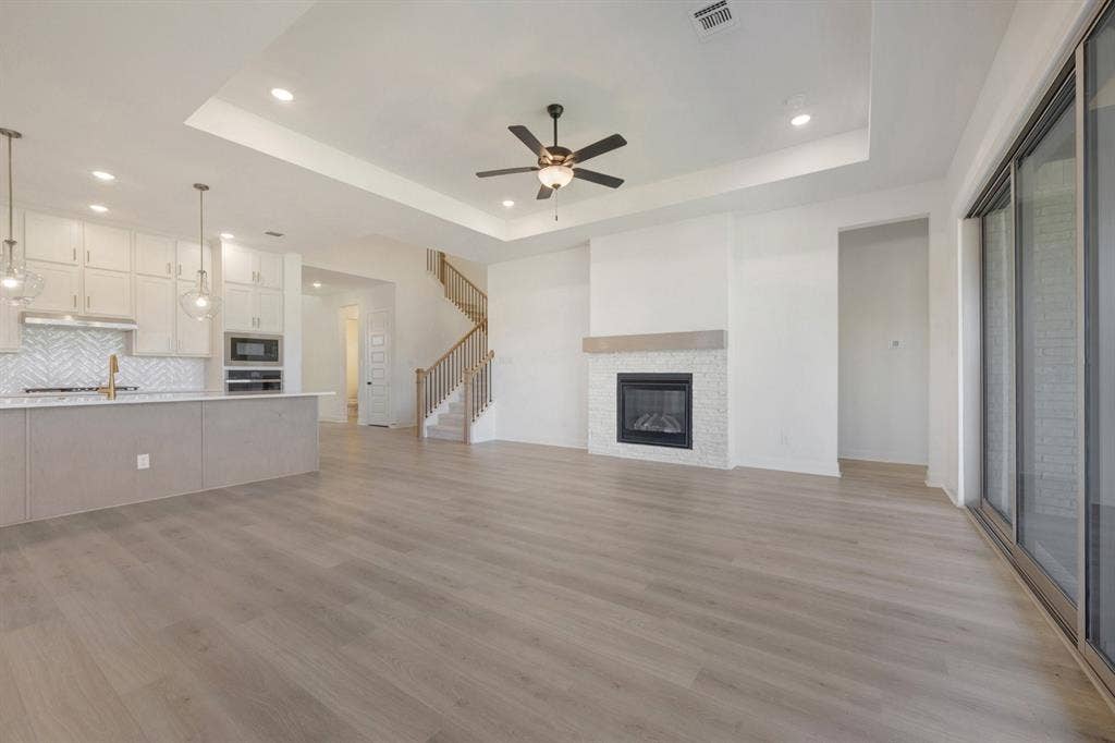 3283 Jersey Drive, Midlothian, TX 76065 Open-concept living area featuring light wood-finish flooring, a contemporary fireplace with a decorative tile surround and wood mantel, and sliding glass doors