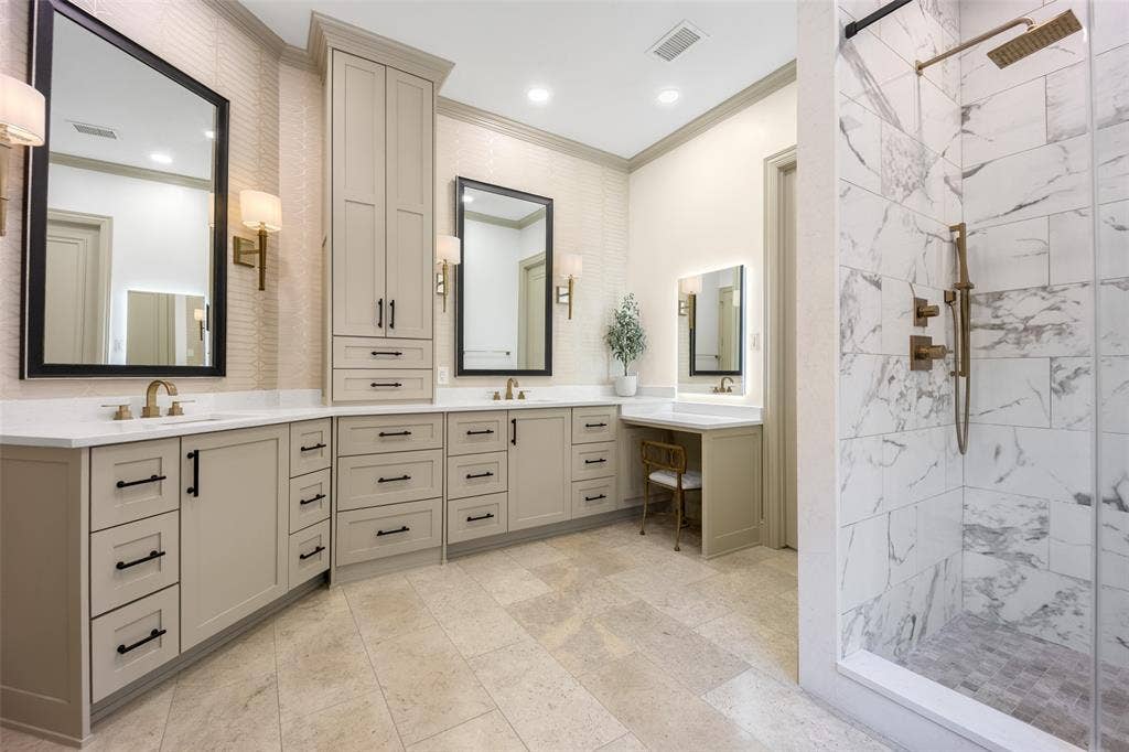 6615 Meadow Road, Dallas, TX 75230 Spa-worthy primary bath has been updated with a neutral, transitional color palette. Marble shower with brass-fitted rainshower, separate soaking tub, a seated lit makeup vanity and tons of storage. A huge walk in closet lies just off the bath.