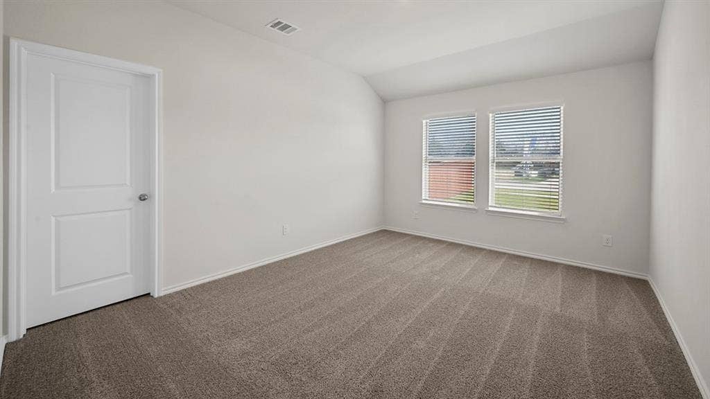 Spare room with dark carpet and vaulted ceiling