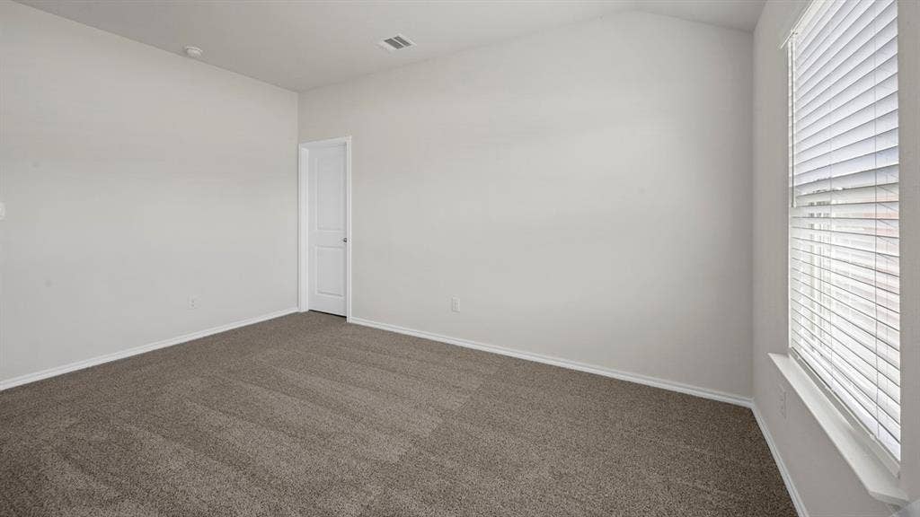 Unfurnished room featuring dark colored carpet, plenty of natural light, and lofted ceiling