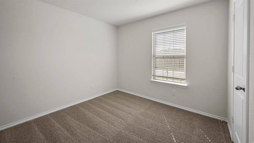 Unfurnished room with dark colored carpet and baseboards