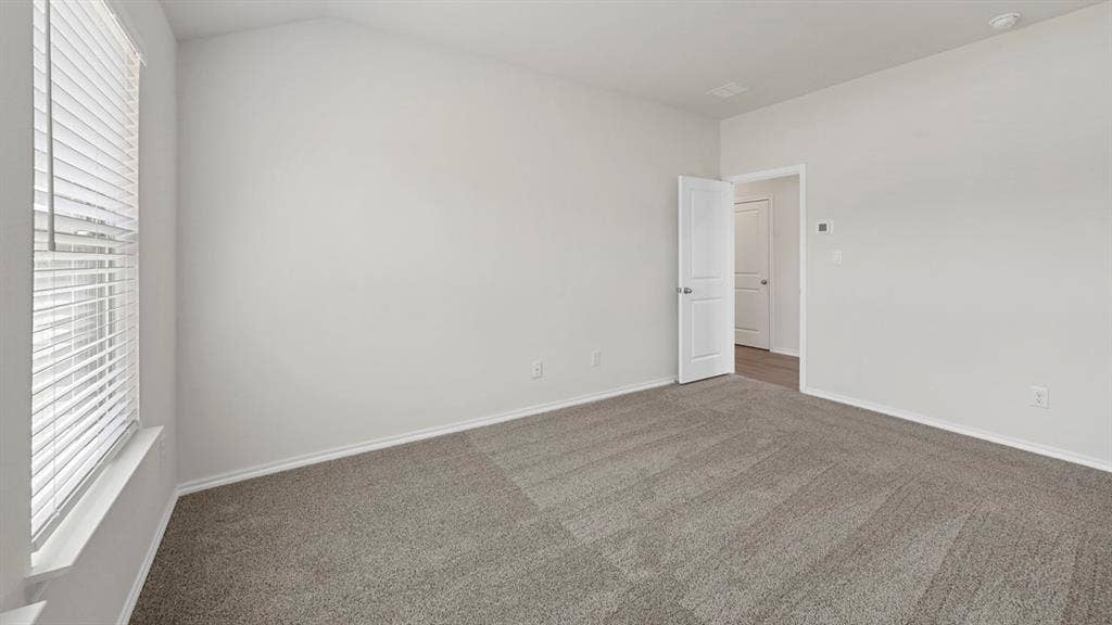 Empty room with dark colored carpet and vaulted ceiling