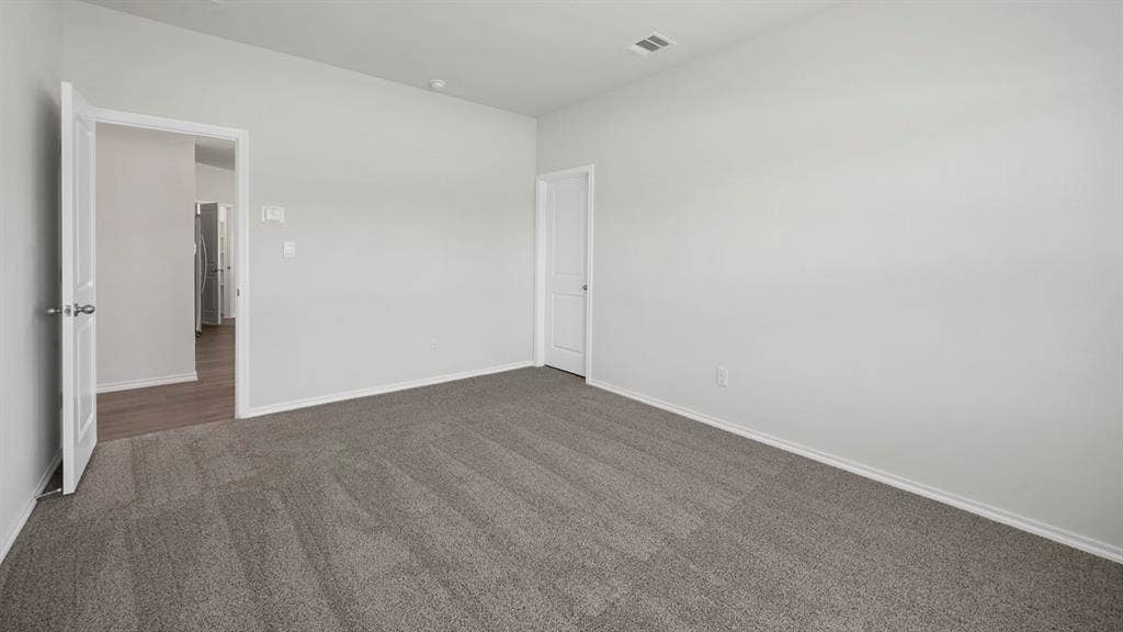 Unfurnished bedroom featuring dark colored carpet and baseboards