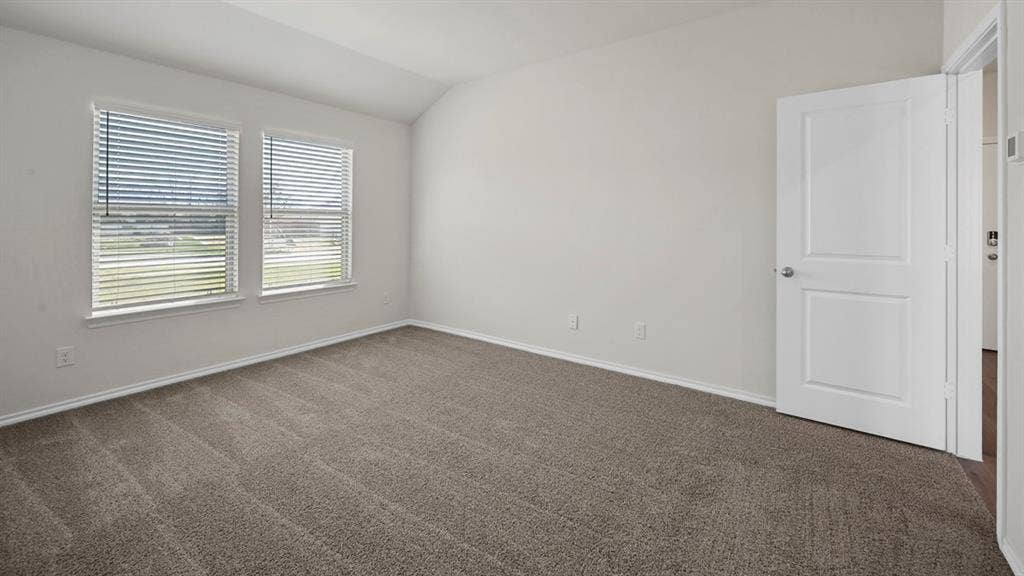Unfurnished room with dark colored carpet and lofted ceiling