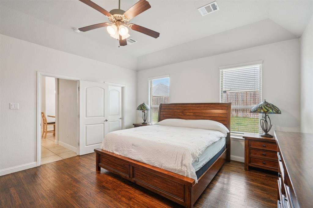 Primary bedroom featuring wood floors and abundant natural light from large windows.