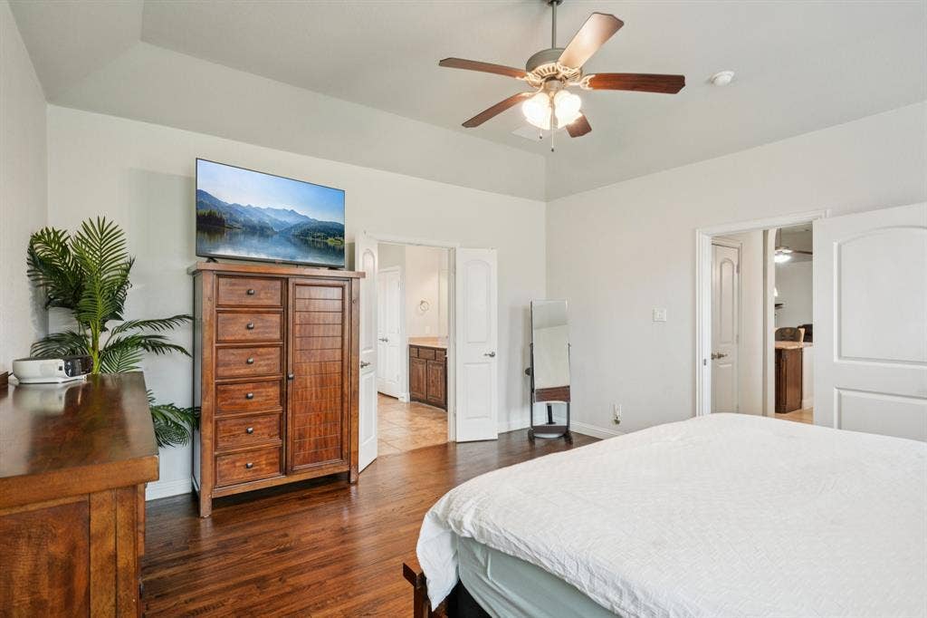 Primary bedroom featuring wood floors and abundant natural light from large windows.