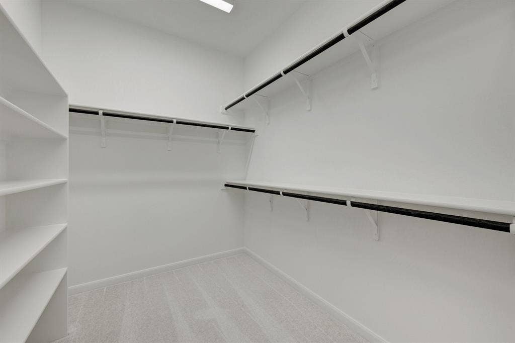 2852 Yampa Drive, McKinney, TX 75071 Spacious walk-in closet featuring built-in shelving, multiple hanging rods, light-colored carpet, and recessed ceiling lighting