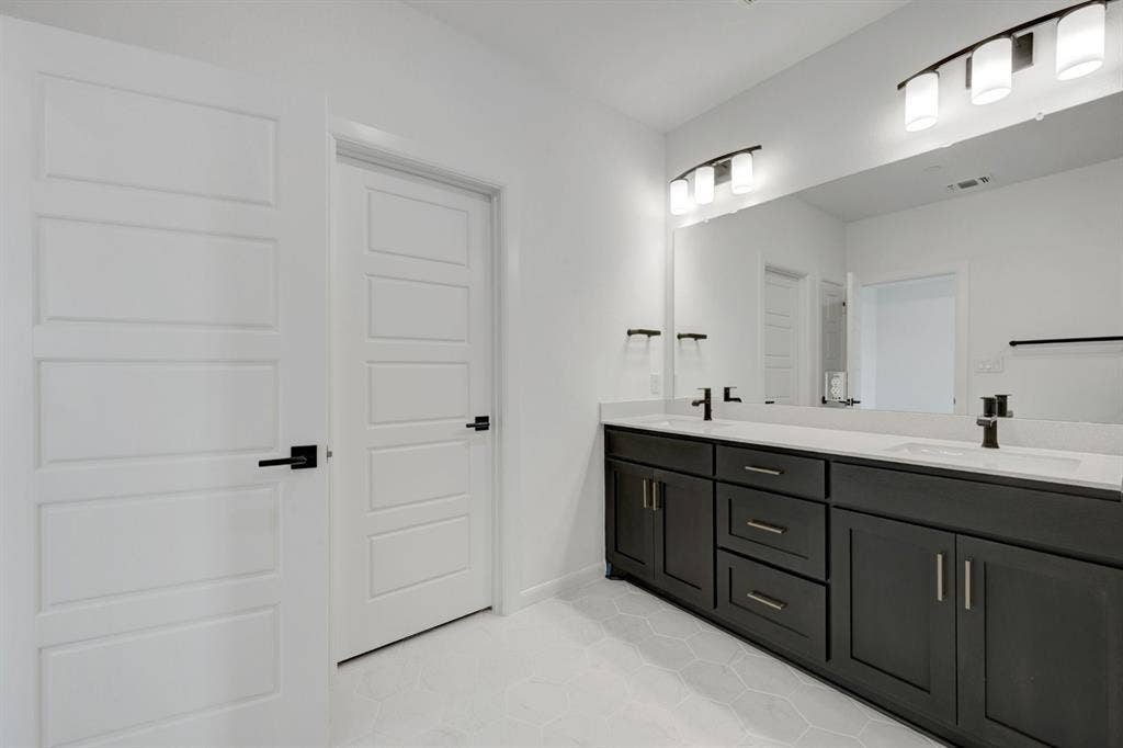 2852 Yampa Drive, McKinney, TX 75071 Dual vanity with dark wood cabinetry, white countertops, and matte black fixtures