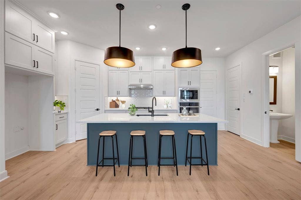 2860 Yampa Drive, McKinney, TX 75071 Modern kitchen featuring a blue island with a white countertop, two pendant lights, recessed lighting, and wood-finish flooring
