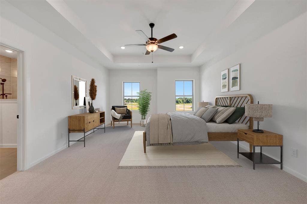 2860 Yampa Drive, McKinney, TX 75071 Spacious room featuring tray ceilings with a ceiling fan, two large windows, light-toned carpeting, and a doorway opening to a bathroom with a tiled shower