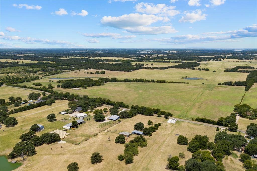 Expansive rural landscape featuring multiple parcels of open land, scattered tree lines, and several residential structures