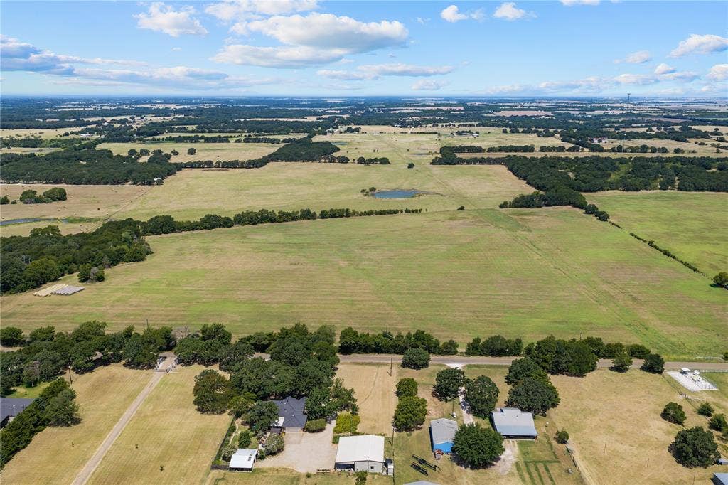 Expansive rural landscape featuring a mix of open fields and mature tree lines
